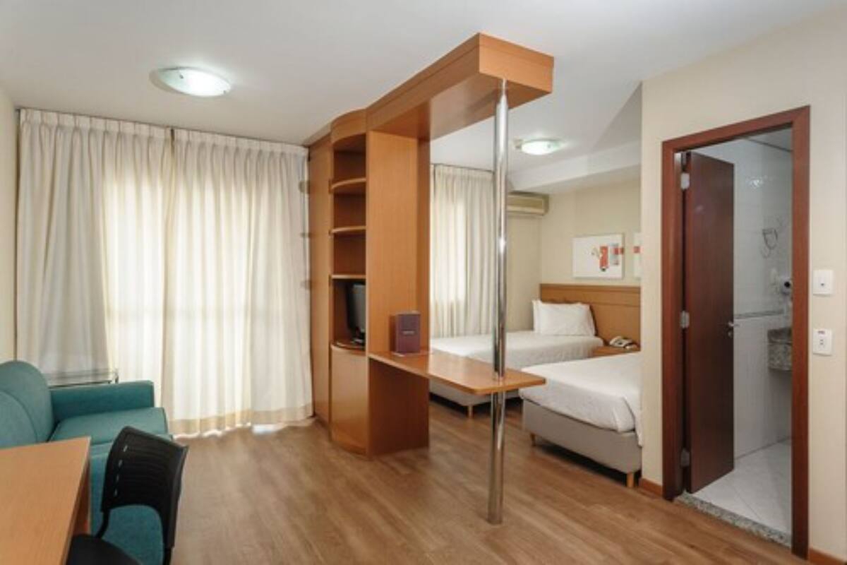 Una habitación de hotel con un escritorio de madera, una cama, un sofá y un televisor.