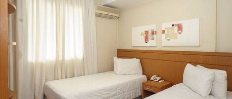 A hotel room with two beds, a nightstand, a telephone, and artwork on the wall.