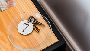 A key ring with keys on a wooden surface with a glass bowl containing a white circular object with the number 7. - Comercial Boutique Azores (Ponta Delgada)