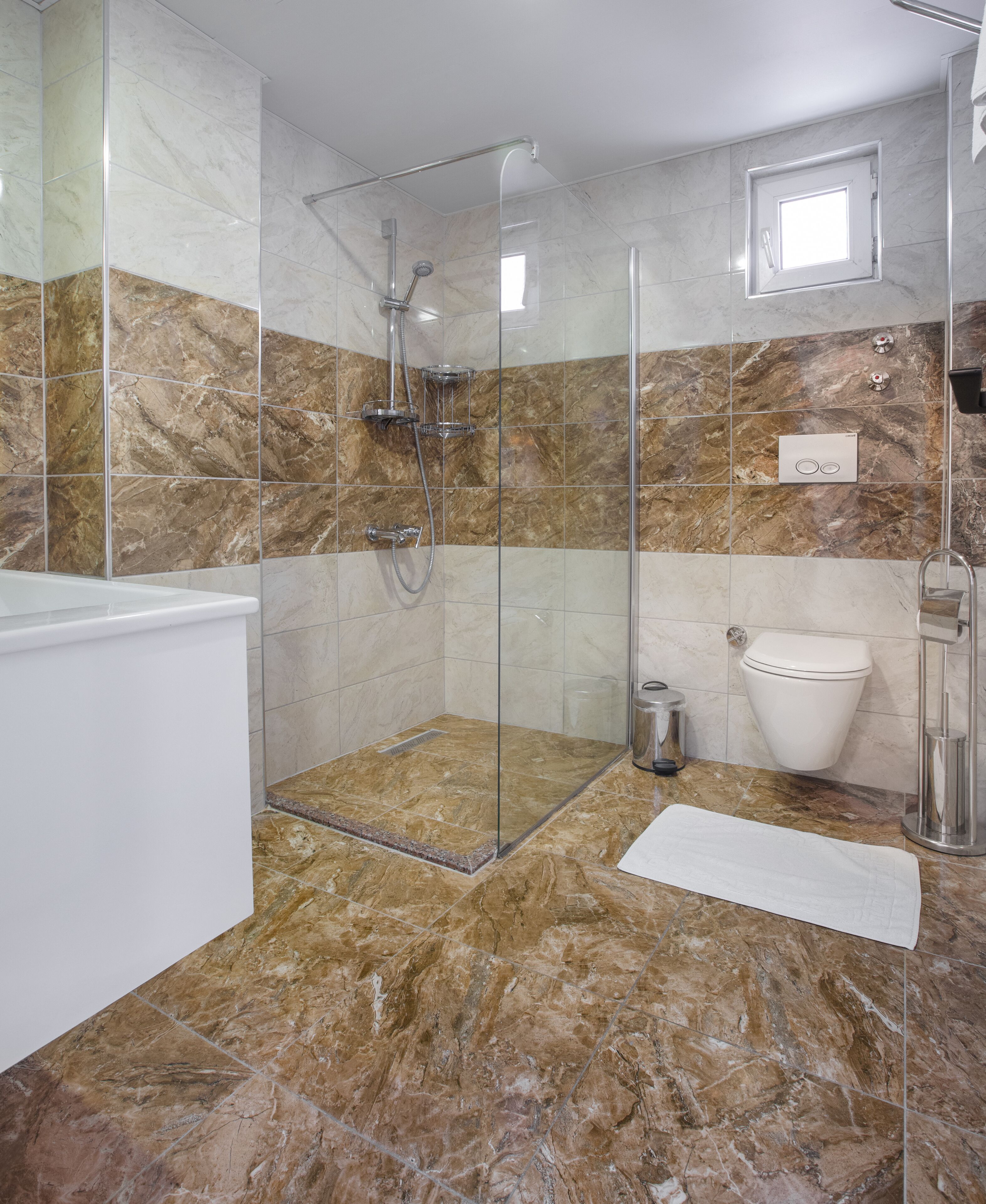 A modern bathroom with a glass-enclosed shower, a white bathtub, and a toilet.