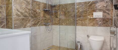 A modern bathroom with a glass-enclosed shower, a white bathtub, and a toilet.