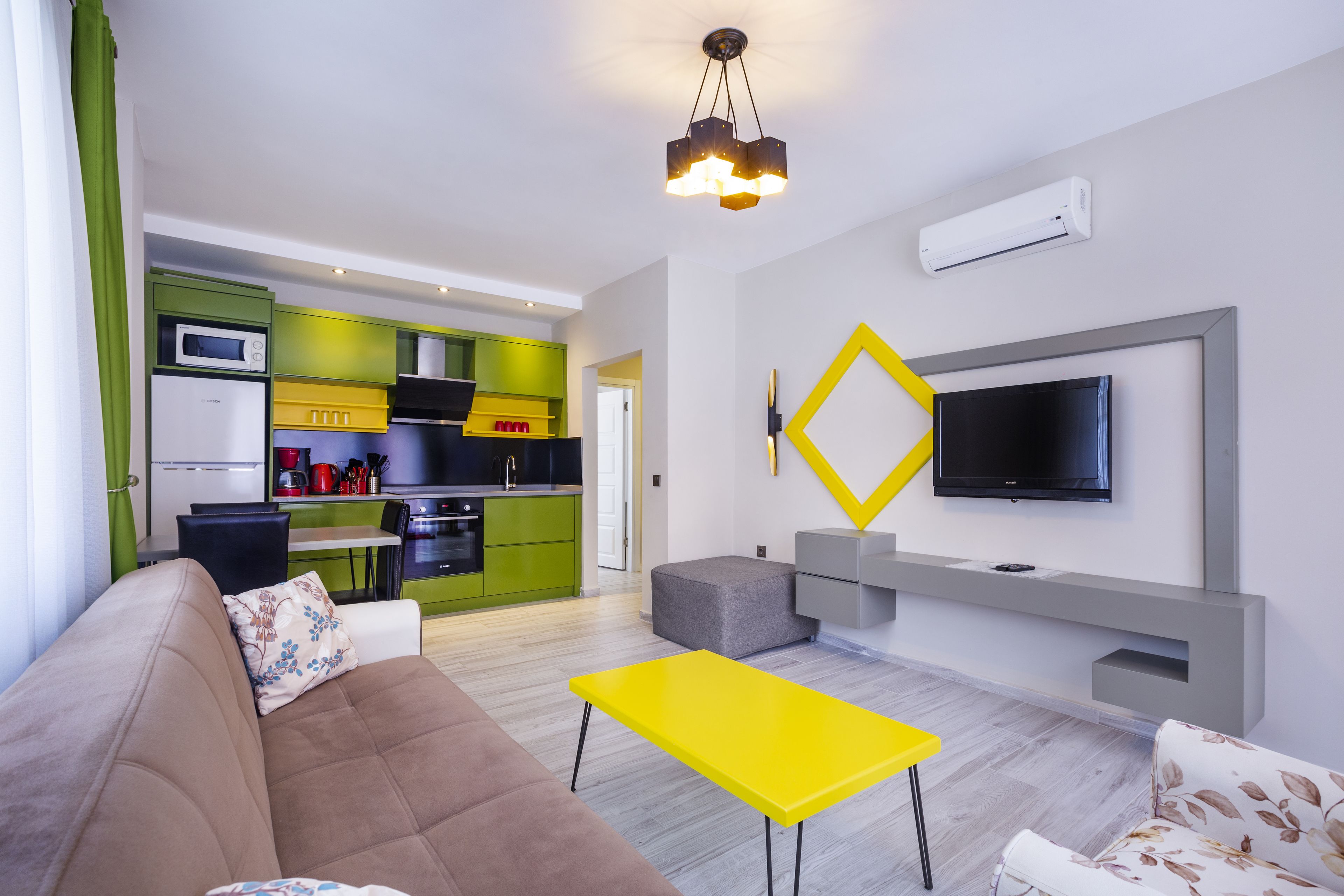 A modern living room with a sofa, a yellow coffee table, and a flat-screen TV mounted on the wall.