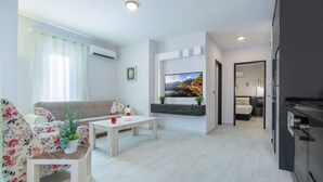 A modern living room with a sofa, coffee table, and a TV mounted on the wall. - Twin Apart Hotel (Alanya)