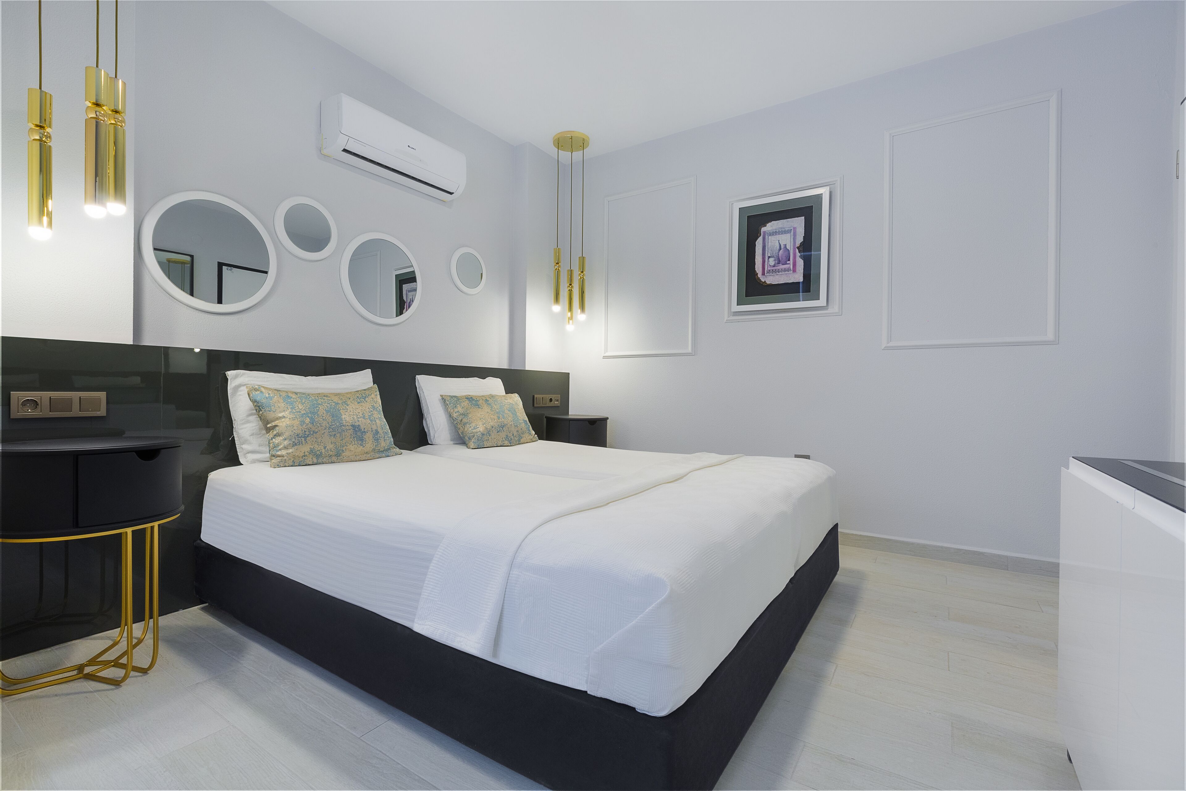 Une chambre moderne avec un grand lit, des tables de chevet, un bureau et un climatiseur fixé au mur.