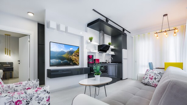 A modern living room with a sofa, a coffee table, and a flat-screen TV mounted on the wall. - Twin Apart Hotel (Alanya)