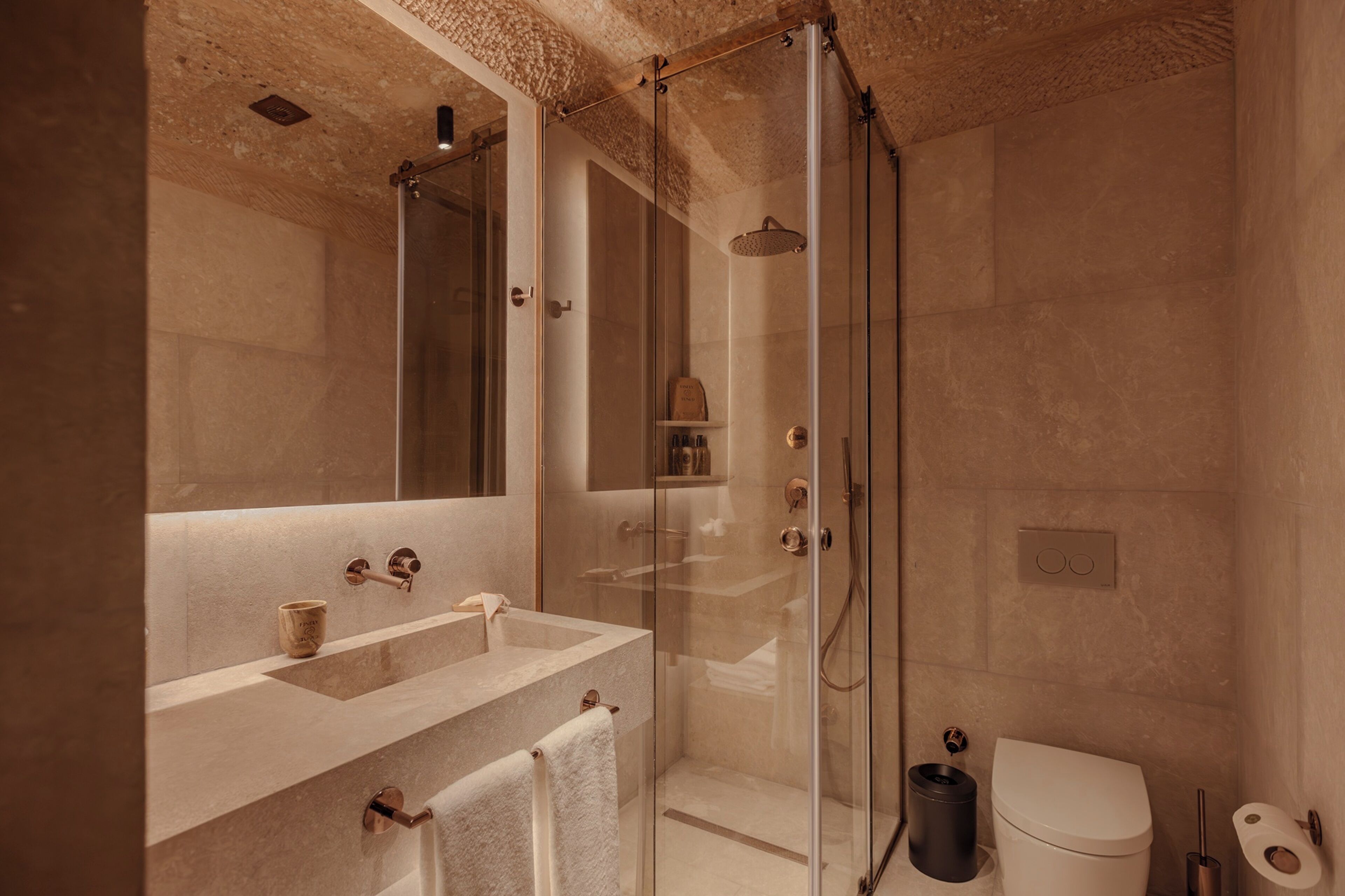 A modern bathroom with a glass-enclosed shower, a sink with a towel, and a toilet.