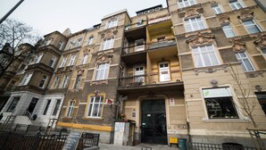 Un edificio de varios pisos con detalles arquitectónicos ornamentados, incluyendo balcones y molduras decorativas.