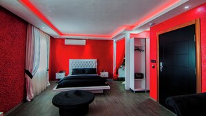 Ein modernes Schlafzimmer mit rotem und weißem Farbkonzept, einem großen Bett, einem Nachttisch und einem Kleiderschrank.