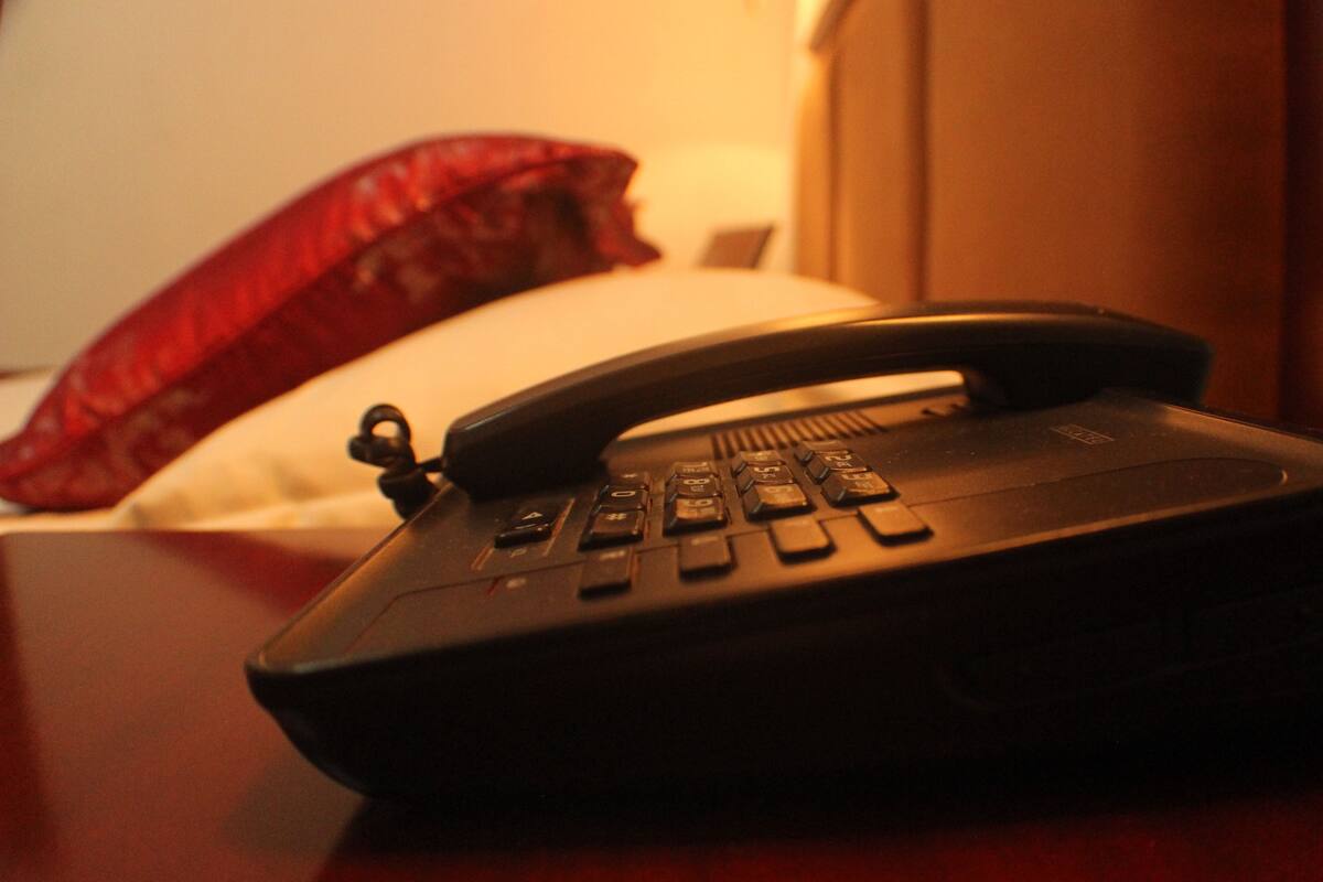 A hotel room with a telephone on a wooden surface.