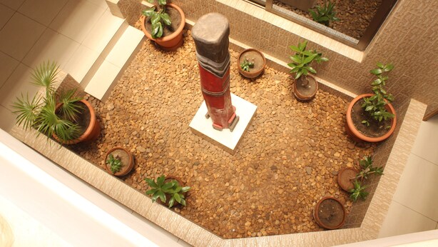 Un petit jardin d’intérieur comprenant diverses plantes en pot et un pilier en pierre décoratif.