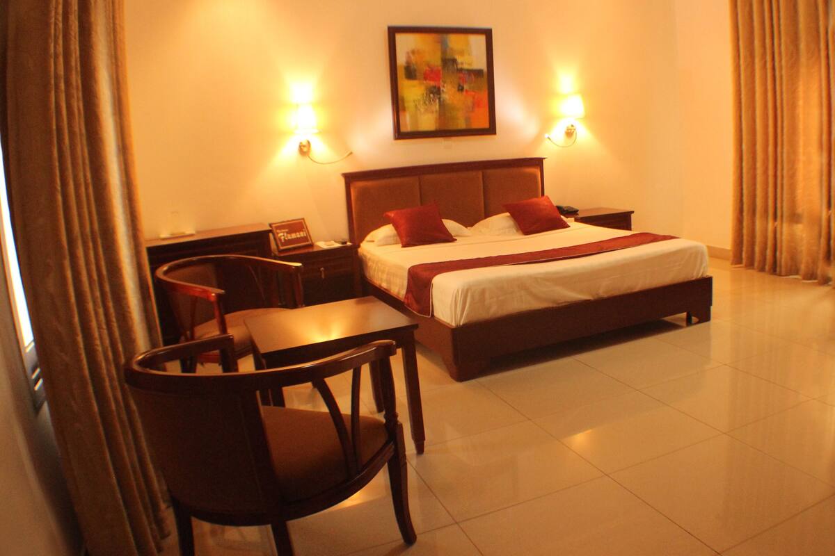 A hotel room with a bed, bedside tables, a desk, and a chair.