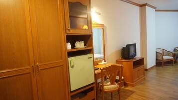 A compact living space with a wooden cabinet, a small refrigerator, a television, and a chair.