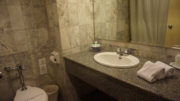 A bathroom with a marble floor, a white sink, a mirror, and a toilet.
