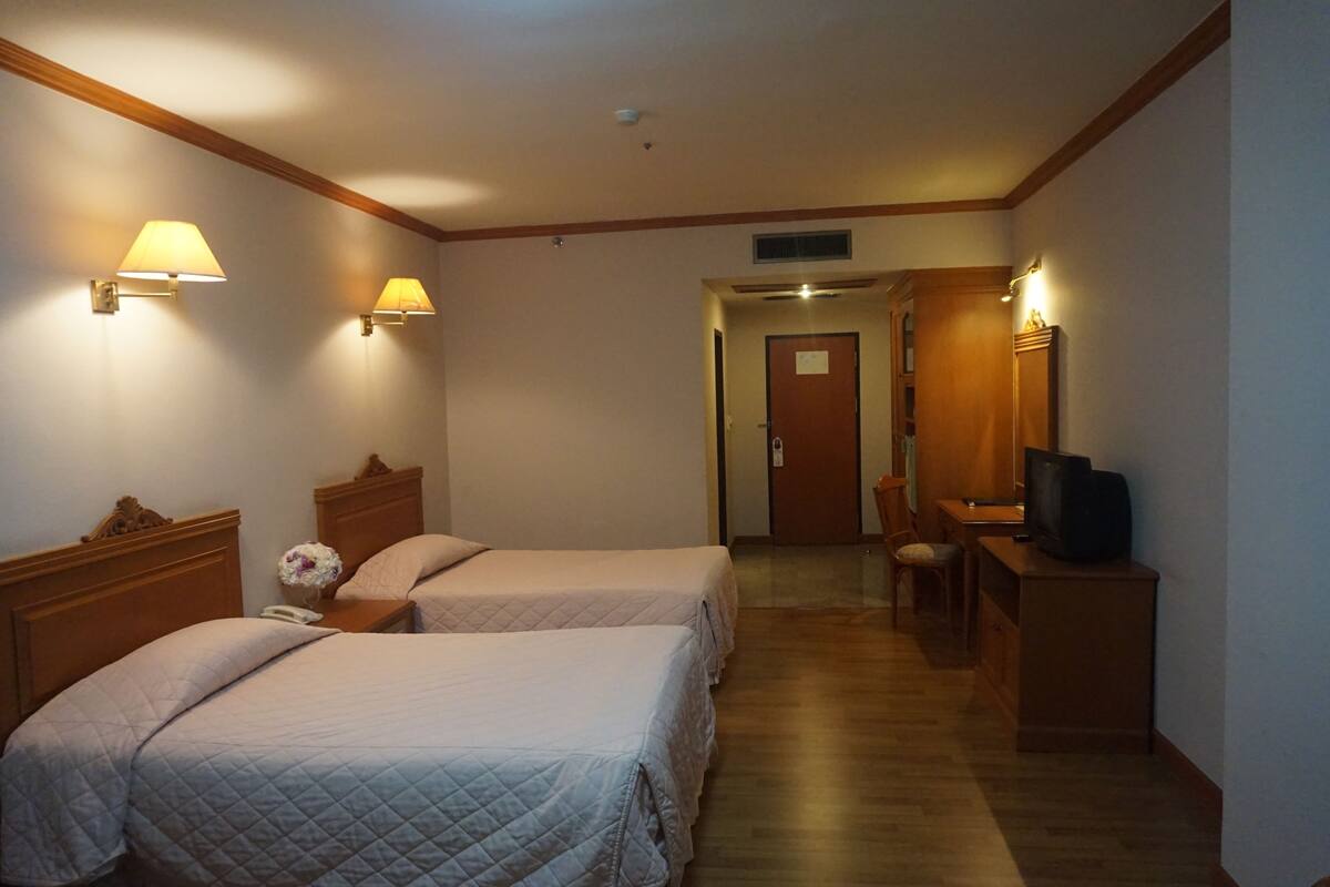 A hotel room with two beds, a desk with a television, and a chair.