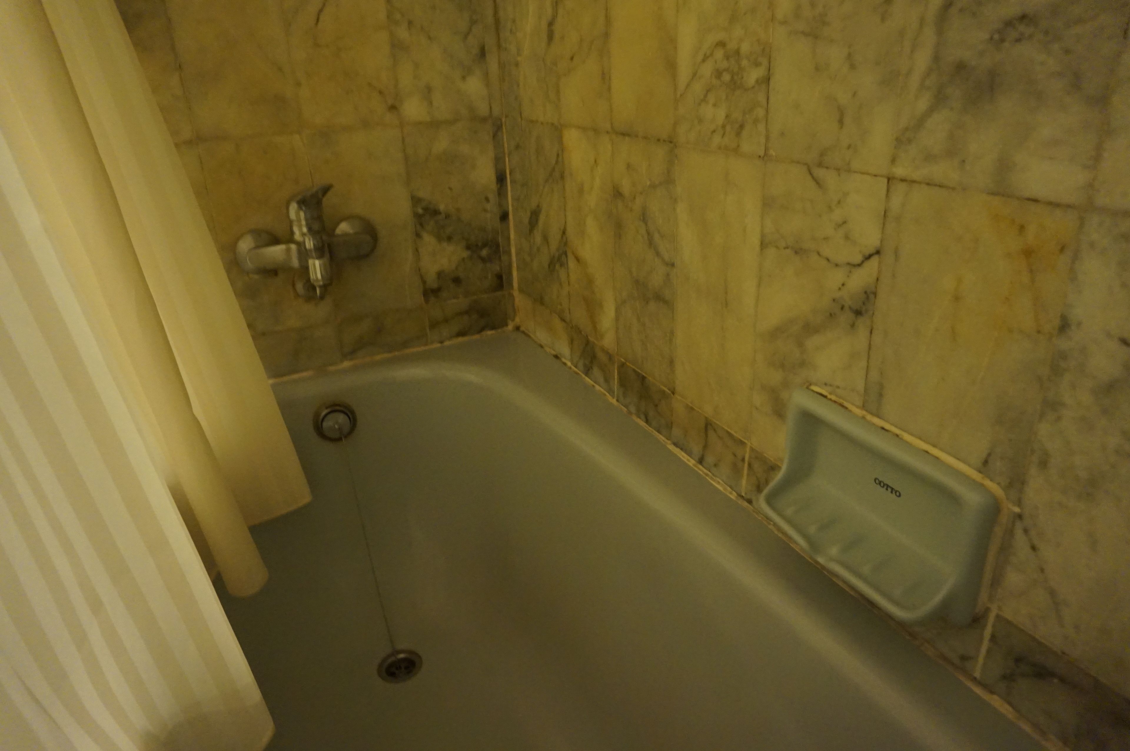 A bathroom with a bathtub, a shower, and a marble wall.