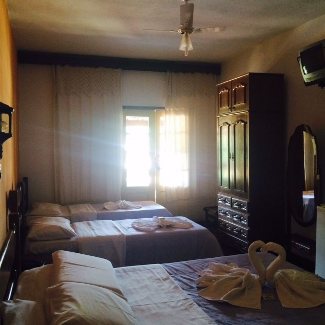 Una habitación de hotel con dos camas, un armario, un televisor y un ventilador de techo.