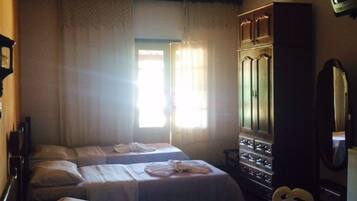 Una habitación de hotel con dos camas, un armario, un televisor y un ventilador de techo.