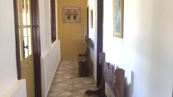 A hallway with patterned flooring, wooden benches, and framed artwork on the walls.