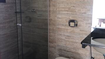 A modern bathroom with a glass shower enclosure, a white toilet, and a sink with a chrome faucet.
