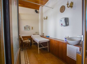 Cozy retreat with a single bed, wooden bench, and compact sink area.