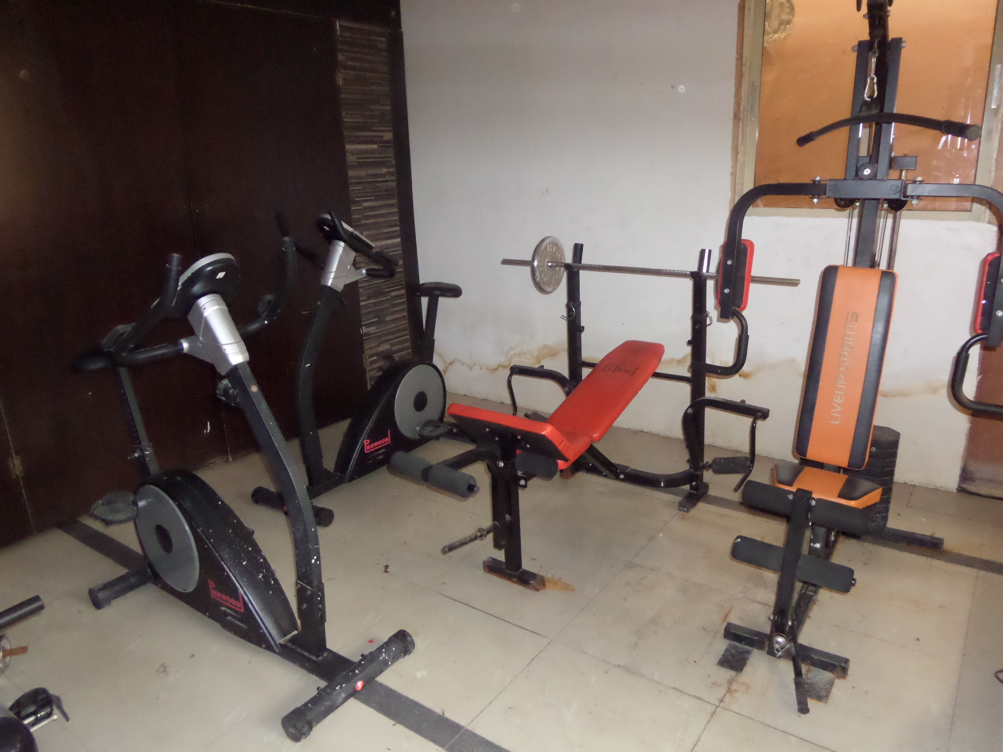 Une salle de sport équipée de matériel d’exercice, notamment un tapis de course, un banc et un support à squats.