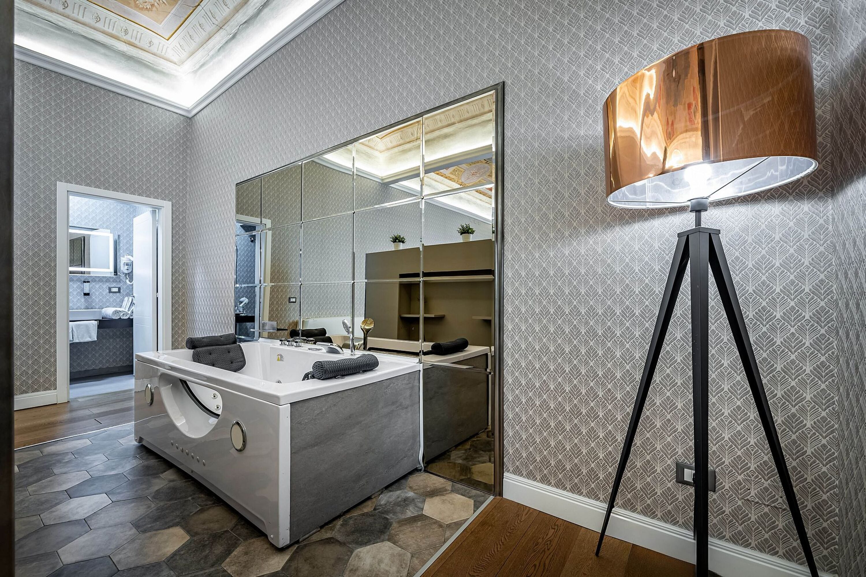 A modern bathroom with a large mirror, a freestanding bathtub, and a floor lamp.