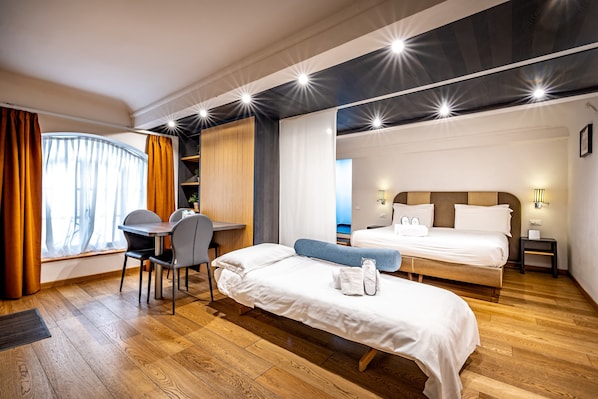 Une chambre d’hôtel avec un lit, un bureau et une chaise. Il y a une fenêtre avec des rideaux et une vue sur l’extérieur.