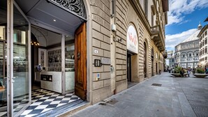 A historic building with a checkered floor, a wooden door, and a sign with a logo. - Martelli 6 Suites and Apartments (Florence)