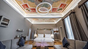 A luxurious hotel room with a large bed, a chandelier, and a decorative ceiling. - Martelli 6 Suites and Apartments (Florence)