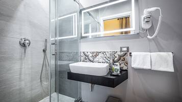 Un baño moderno con cabina de ducha de vidrio, un lavamanos blanco y un perchero para toallas.