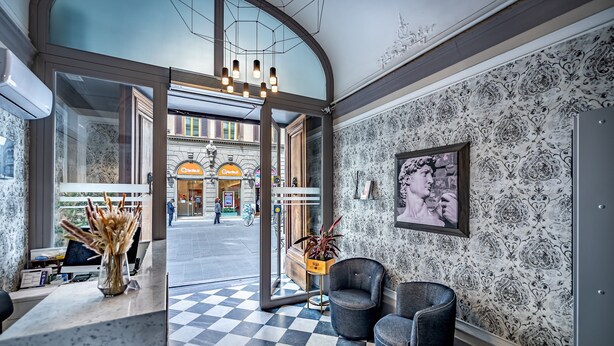A hotel lobby with a checkered floor, a reception desk, and a large window overlooking the street. - Martelli 6 Suites and Apartments (Florence)