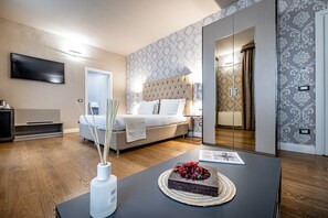 A modern hotel room with a bed, bedside table, lamp, and a flat-screen TV. - Martelli 6 Suites and Apartments (Florence)