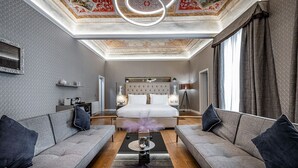 A modern hotel room with a large bed, two sofas, a coffee table, and a chandelier. - Martelli 6 Suites and Apartments (Florence)