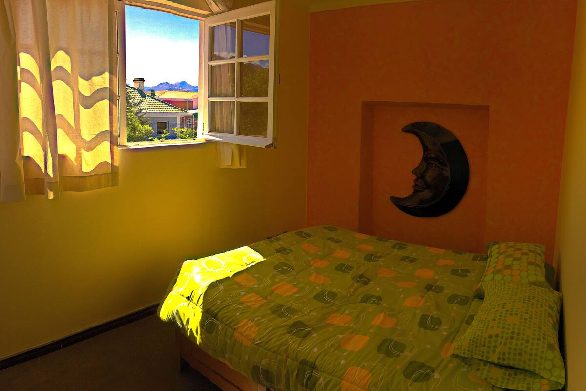 Ein Schlafzimmer mit einem Bett, einem Fenster mit Vorhängen und einer Wand mit Monddeko.
