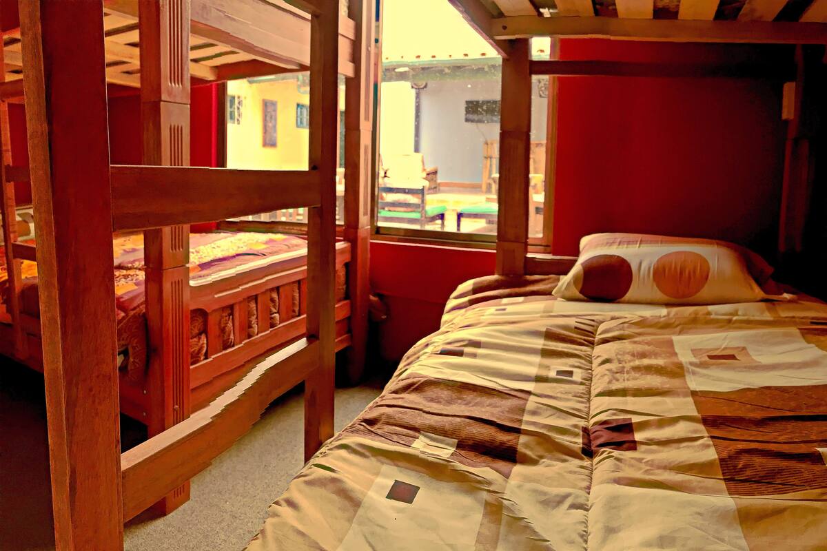 Ein Zimmer mit einem Holzstockbett und einem Einzelbett mit einer Steppdecke.