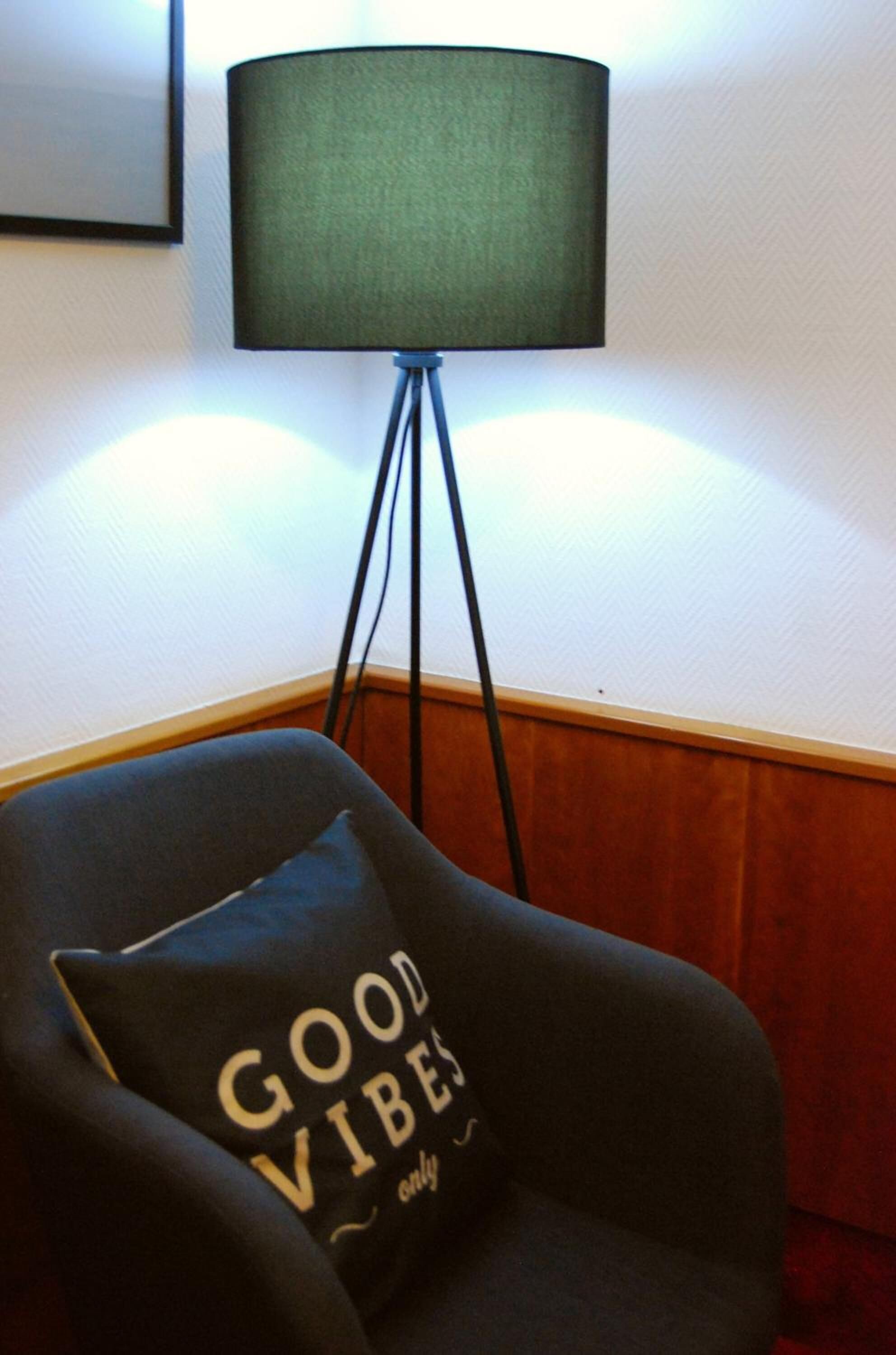 Rincón de una habitación con una silla y una lámpara de pie.