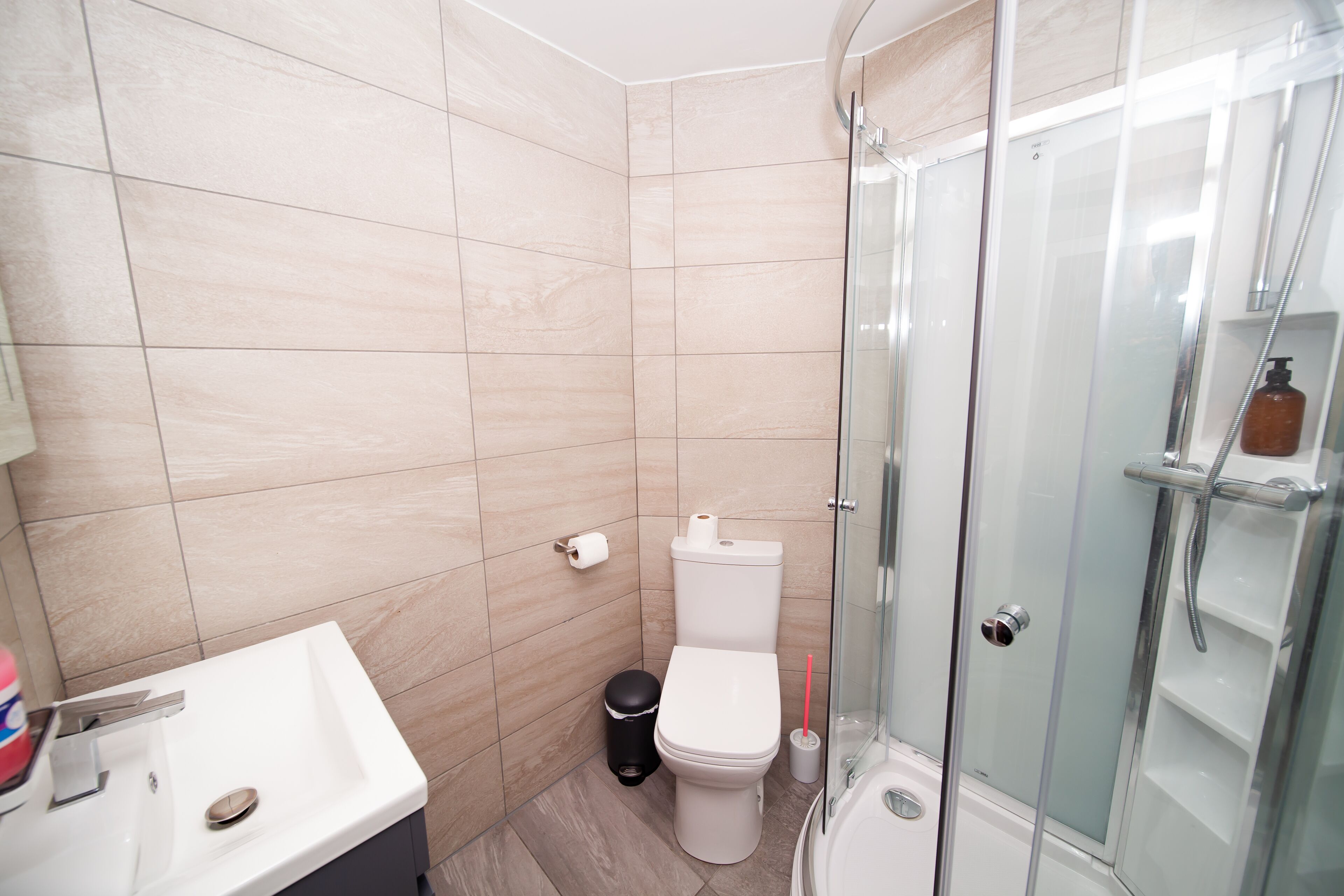 A modern bathroom with a glass-enclosed shower, a white sink, and a toilet.
