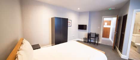 Una habitación de hotel con una cama grande, un armario, un escritorio y un televisor.
