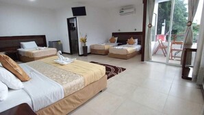 A hotel room with two beds, a flat-screen TV, a small table, and a balcony with a chair. - Hotel Deja Vu (Puerto Ayora)