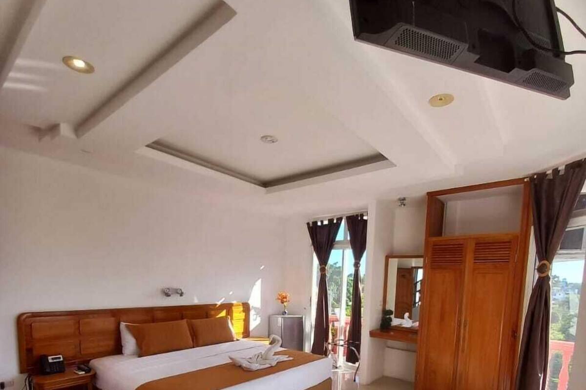 Une chambre d’hôtel moderne avec un grand lit, des meubles en bois et un téléviseur fixé au mur.