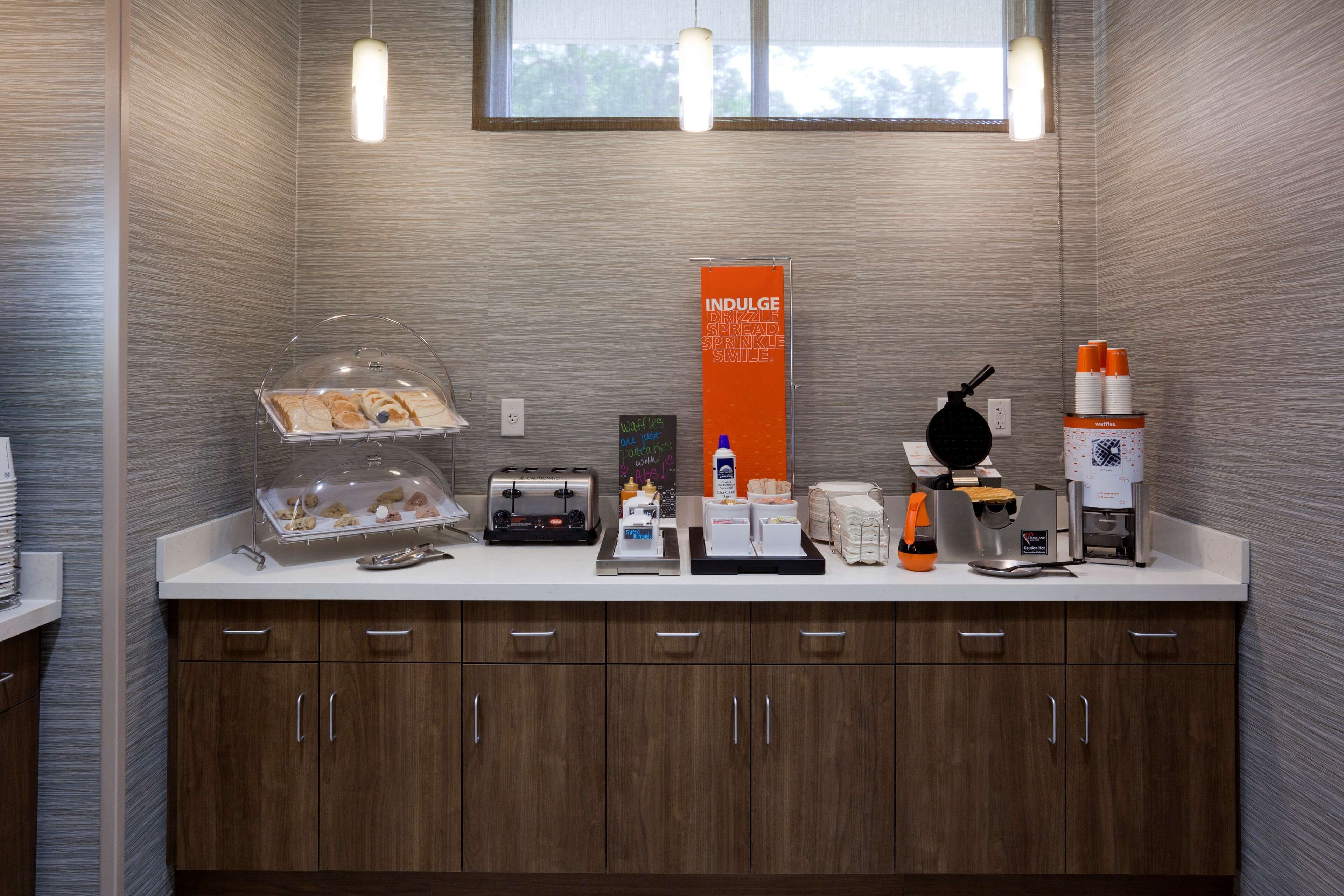 A modern kitchen with a countertop, toaster, coffee maker, and a sign promoting indulgence.