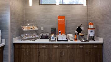A modern kitchen with a countertop, toaster, coffee maker, and a sign promoting indulgence.