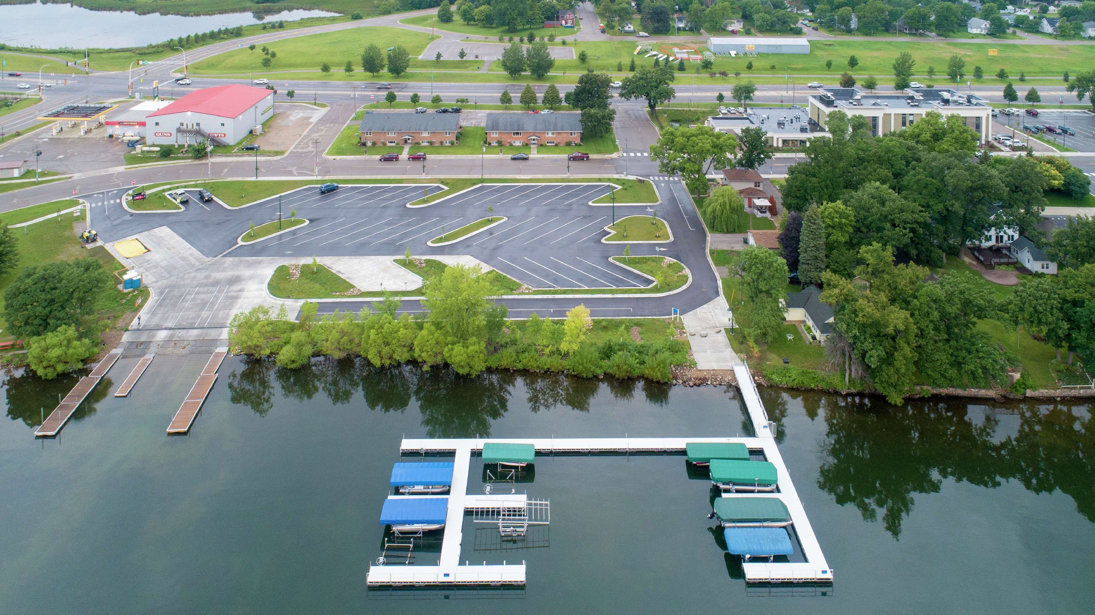 Vue aérienne d’un parking avec une marina où sont amarrés des bateaux, le tout surplombant une étendue d’eau.