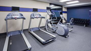 A gym with treadmills, elliptical machines, and dumbbells.