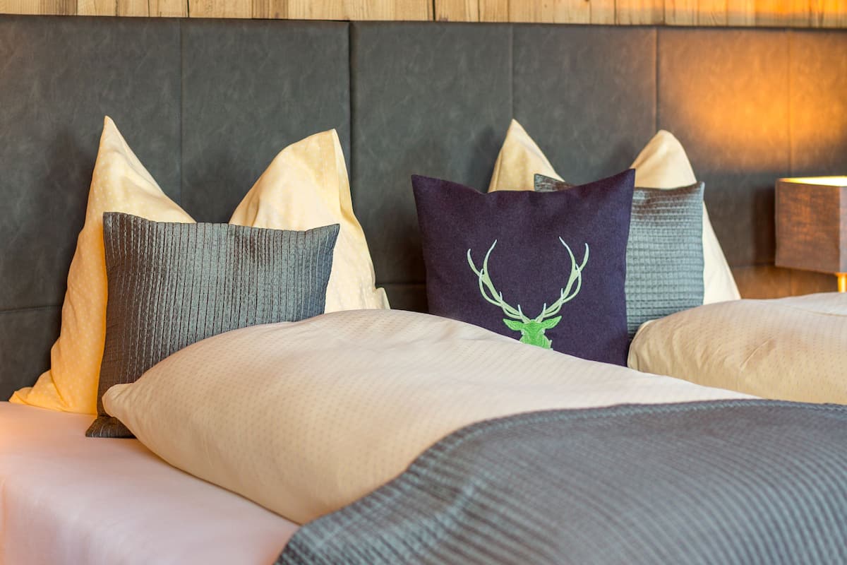 A neatly made bed with a variety of pillows and a headboard with a wooden panel design.