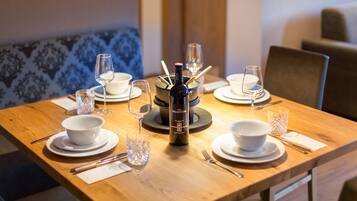 A dining table set with white bowls, plates, and cutlery, a bottle of wine, and glasses.