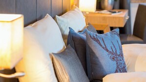 Una habitación de hotel con cabecera de madera, una mesita de noche con lámpara y un arreglo floral.