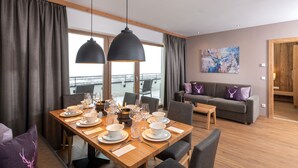Un comedor con una mesa de madera lista para una comida, un sofá y un cuadro en la pared.