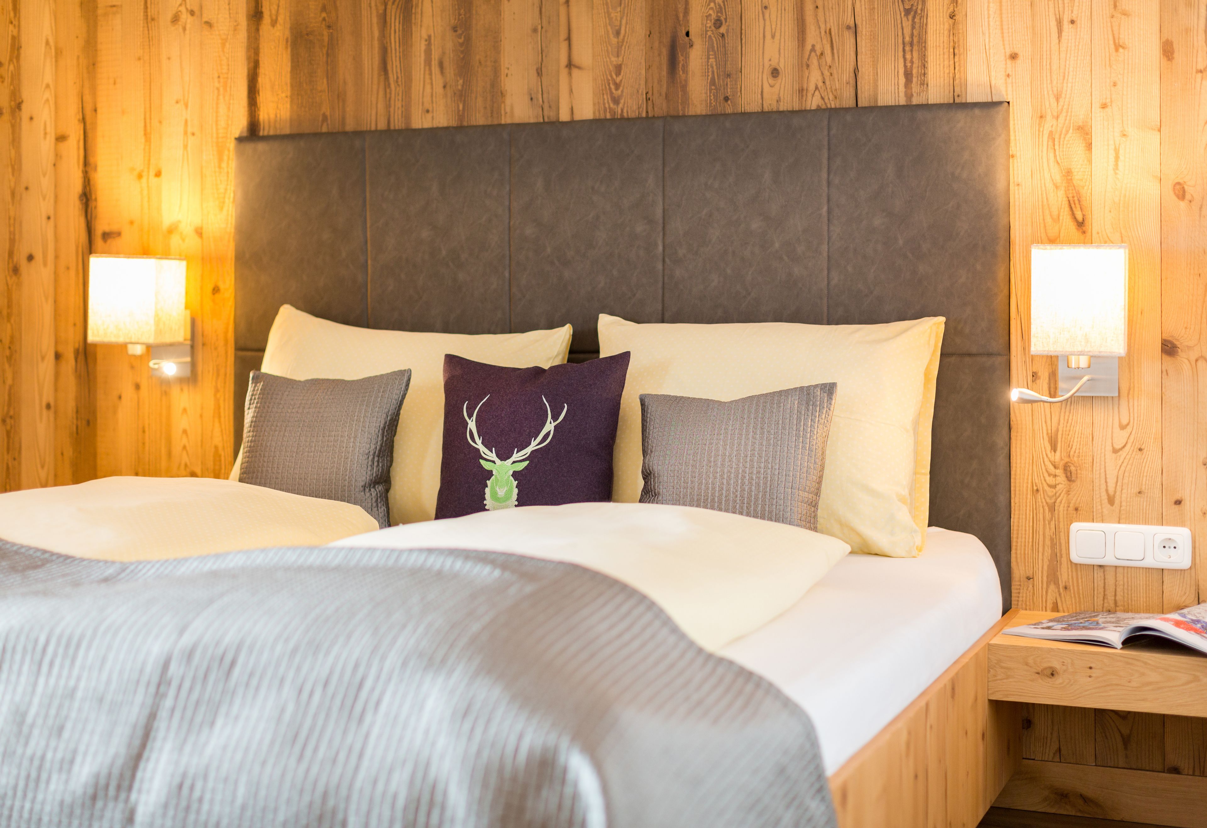 A bed with a headboard, pillows, and a bedside table with a lamp.