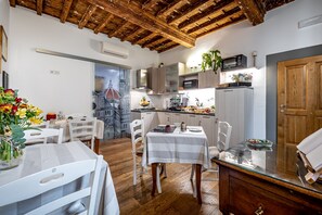 Una zona de menjador amb sostre de fusta, cadires blanques i taula amb mantell blanc.